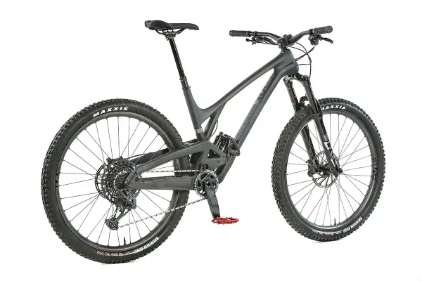 A dark grey Evil Offering mountain bike, ready for an evil offering review. Features Maxxis tires and red pedals.