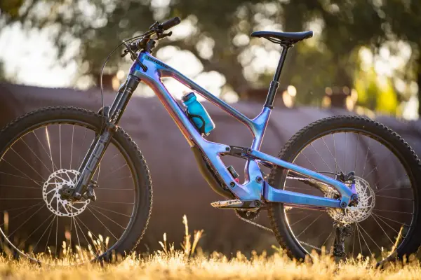 A stunning 2018 Cannondale Jekyll mountain bike with a iridescent blue frame, parked in golden hour light.